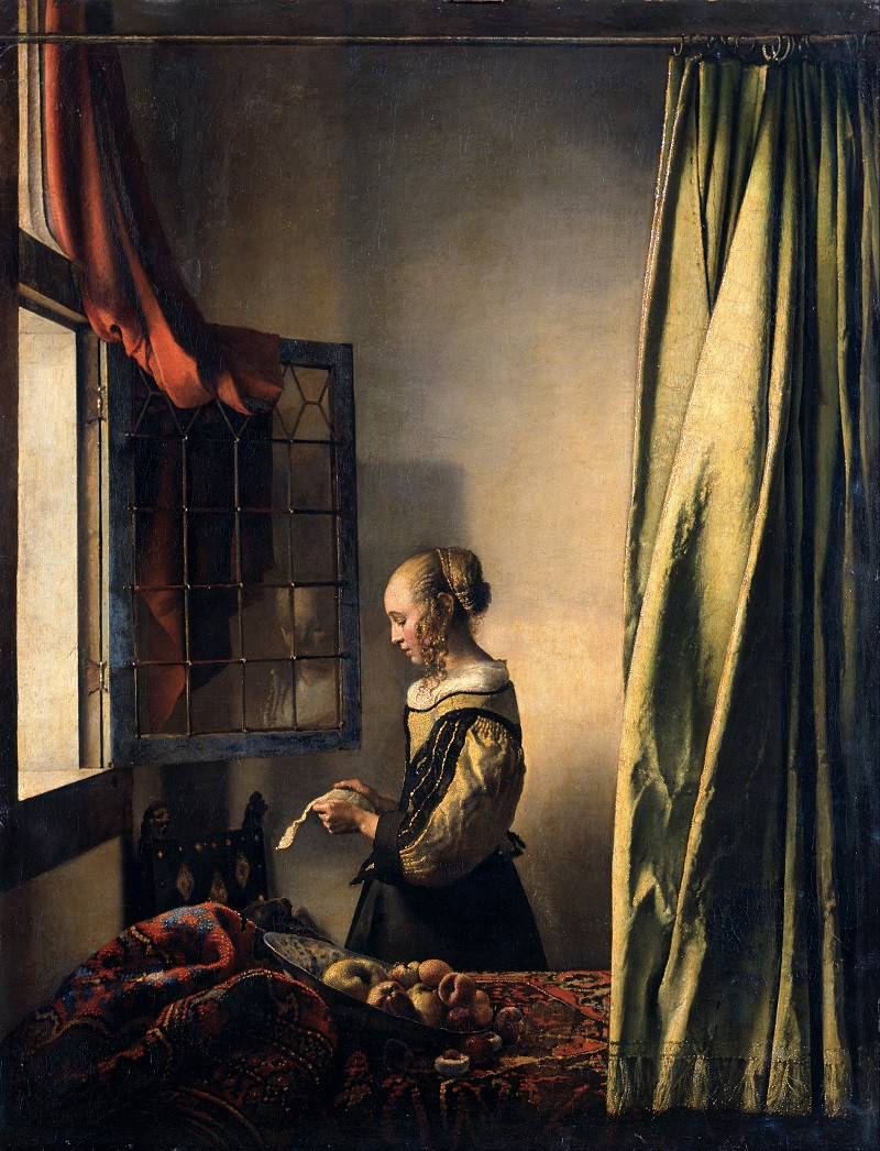 Girl reading a letter in front of the open window