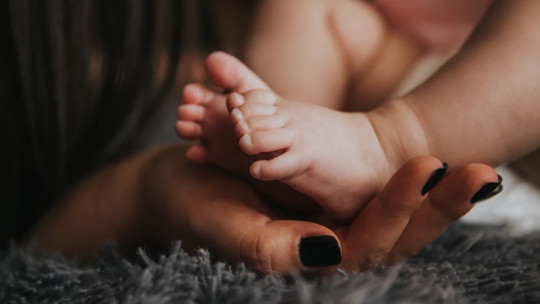 The feet of a baby and the hands of a mother.